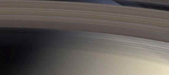 Cette image prsente une vue  travers l'anneau C, le plus proche de Saturne, et  travers la division Cassini qui est un espace de 4 800 km de large qui dcrit un arc  travers le haut de l'image et spare optiquement l'pais anneau B de l'anneau A.